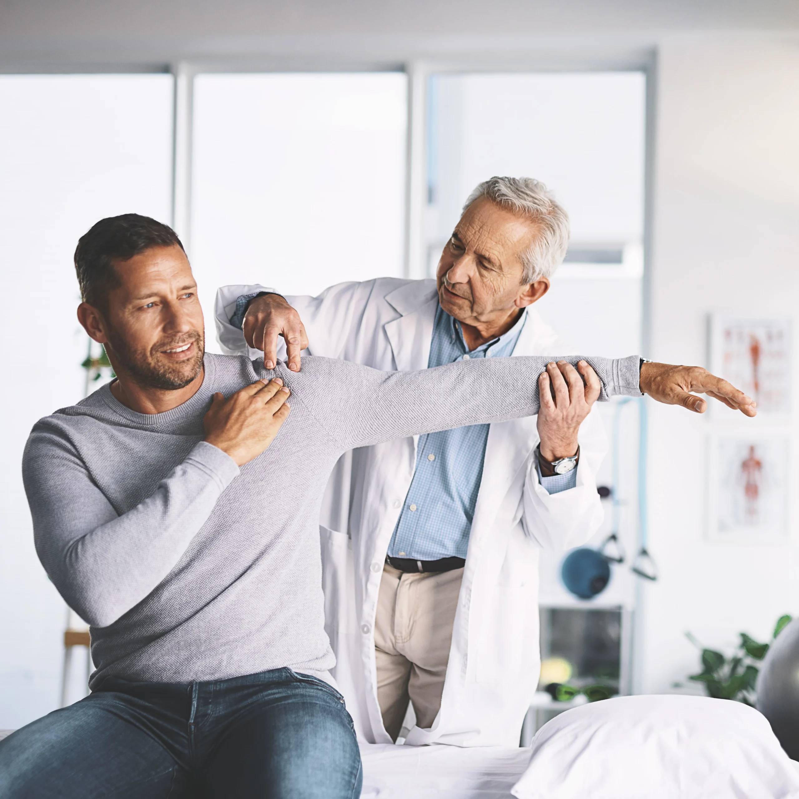Patient getting arm examined doctor indoors at East Hills Physiotherapy in Calgary