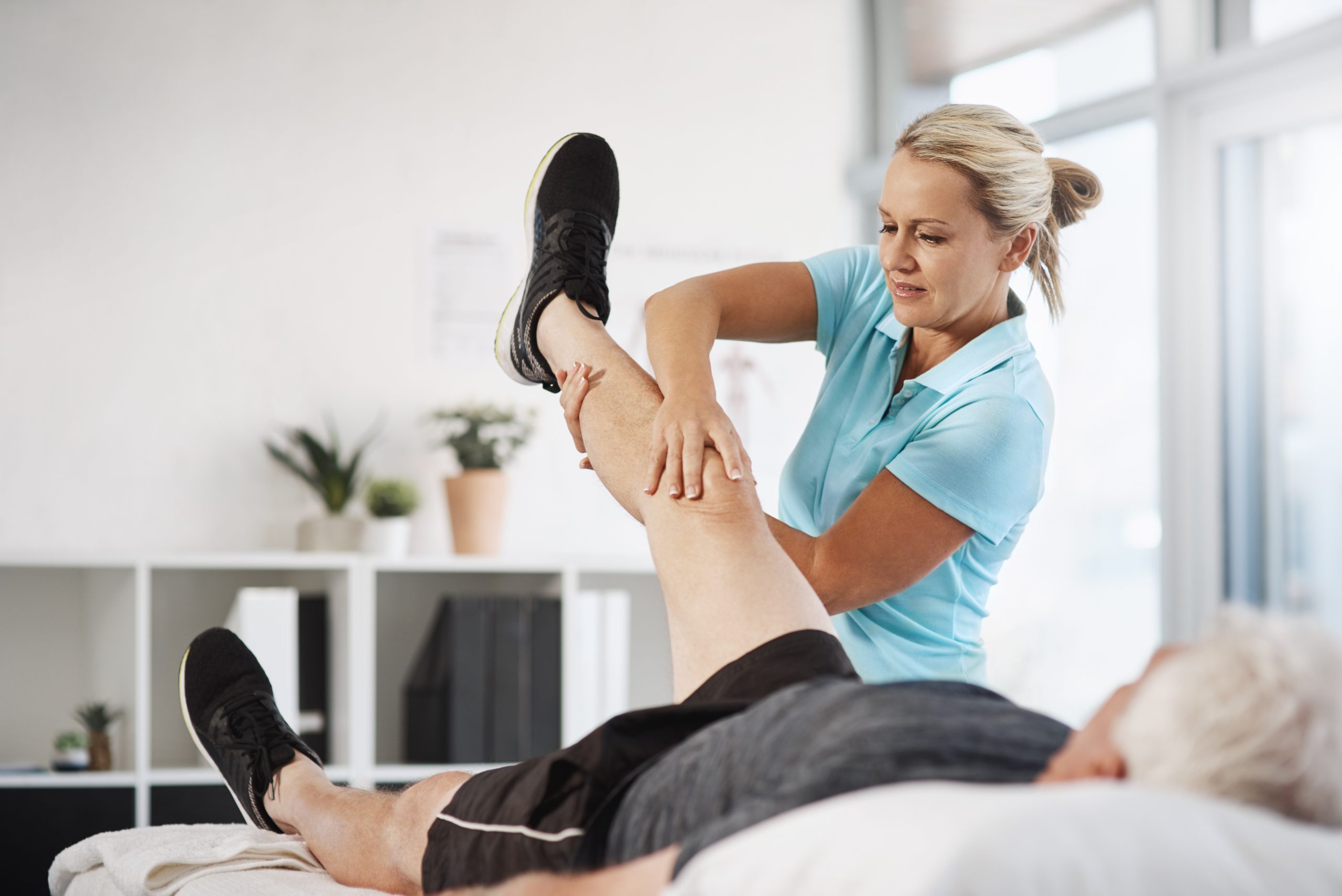Physical therapist helping patient with leg exerci at East Hills Physiotherapy in Calgary